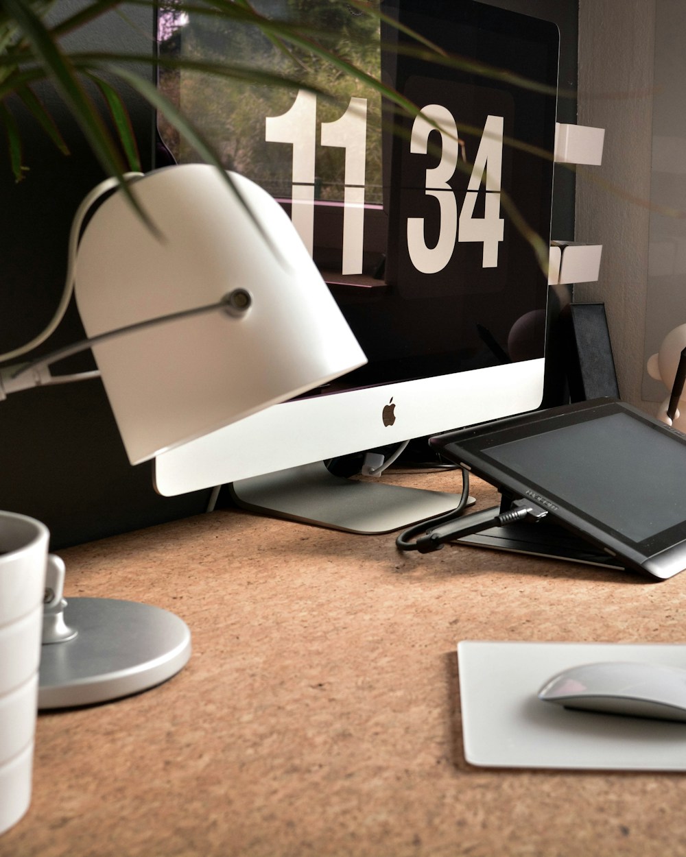 A bright, uncluttered desk with a computer, lamp, and green plant